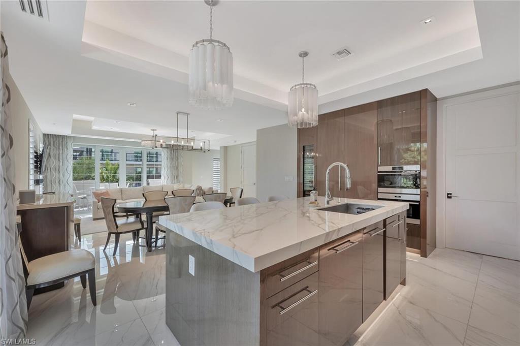 490 5th Street South, Unit 101 Naples, FL 34102 - Photo 17 of 50 a kitchen with a stove a table and chairs