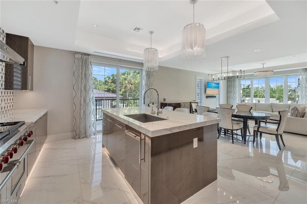 490 5th Street South, Unit 101 Naples, FL 34102 - Photo 18 of 50 a kitchen with a stove and chairs