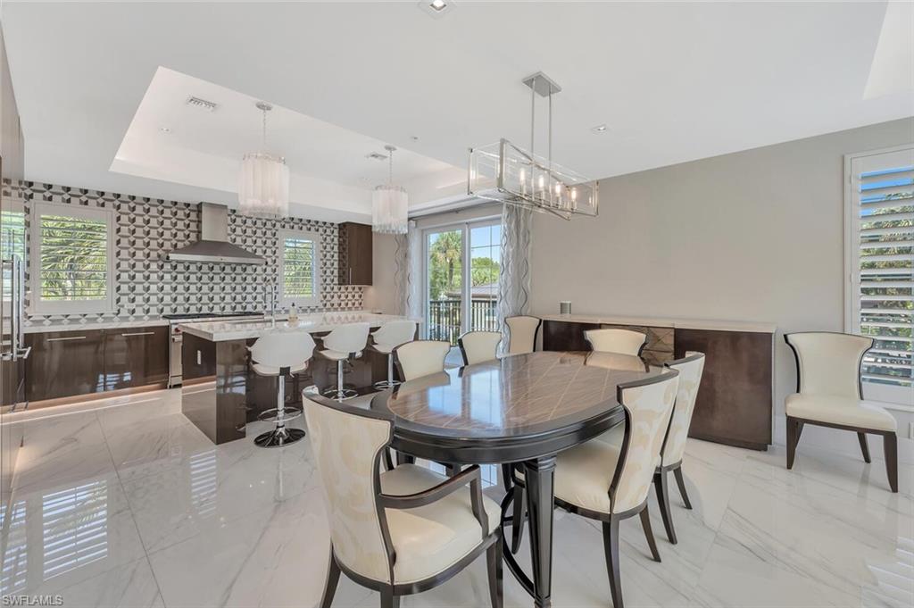 490 5th Street South, Unit 101 Naples, FL 34102 - Photo 20 of 50 a view of a dining room and livingroom with furniture wooden floor a rug a flat screen tv and a chandelier