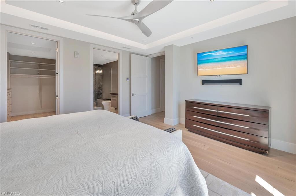 490 5th Street South, Unit 101 Naples, FL 34102 - Photo 30 of 50 a bedroom with a bed and a chandelier