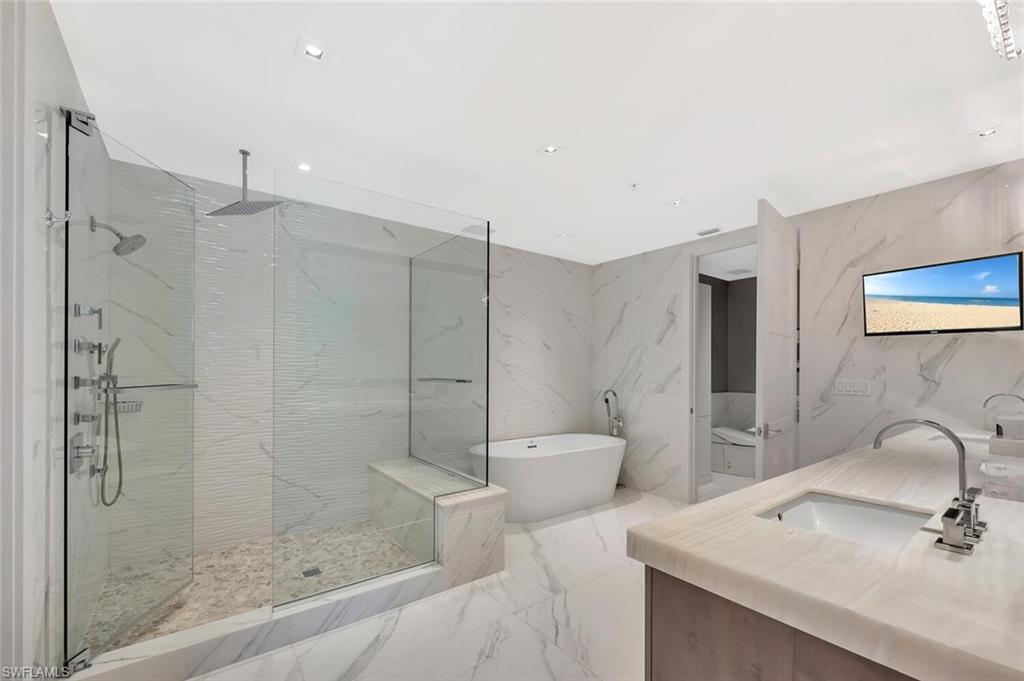 490 5th Street South, Unit 101 Naples, FL 34102 - Photo 38 of 50 a bathroom with a shower sink mirror and toilet