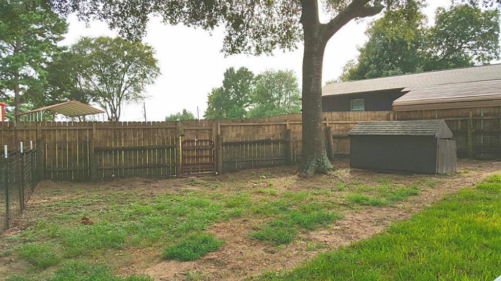 13289 Fm 2432 Road Willis, TX 77378 - Photo 7 of 7 a view of a backyard with brick wall and a large tree