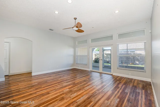 an empty room with wooden floor and windows
