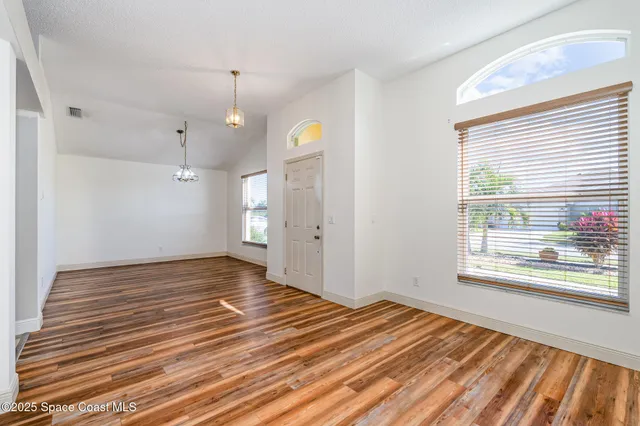 a view of empty room with wooden floor and window
