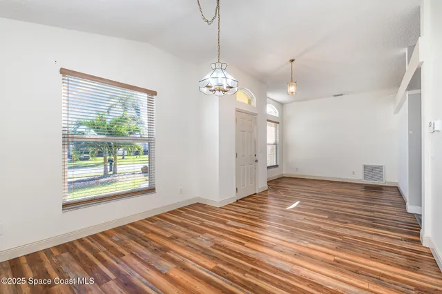 a view of a room with wooden floor chandelier and windows