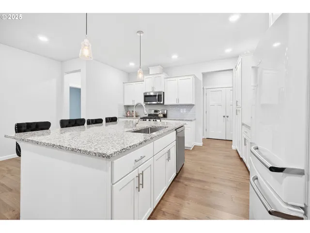 a large kitchen with stainless steel appliances kitchen island a large counter top a stove a sink dishwasher and a refrigerator