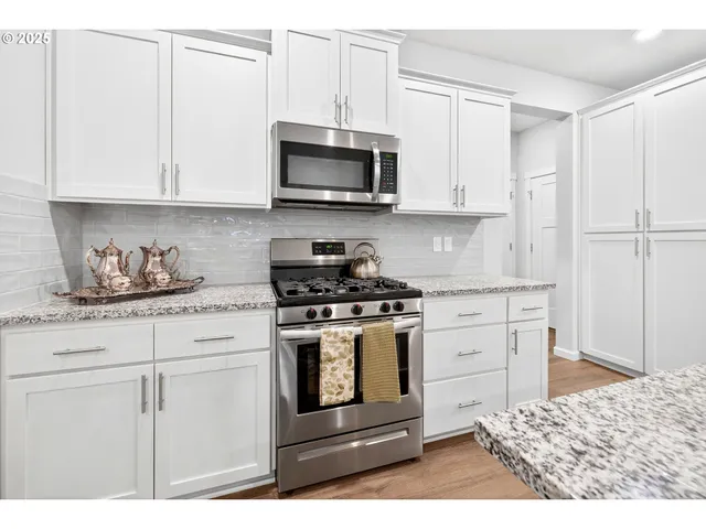 a kitchen with stainless steel appliances granite countertop a stove a sink and a microwave