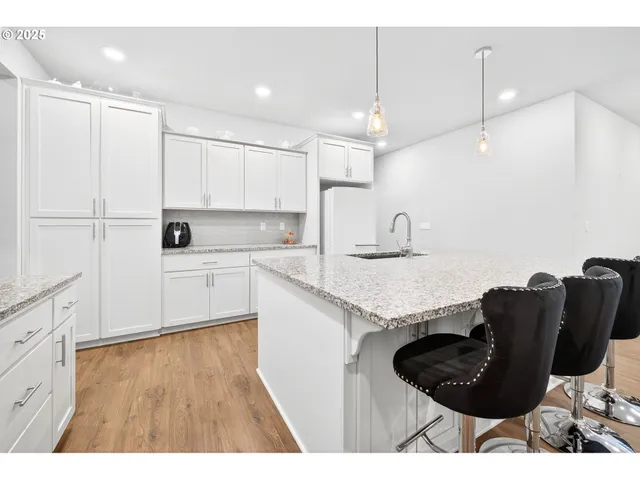 a kitchen with kitchen island granite countertop a sink a counter space appliances and cabinets