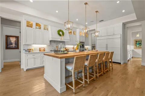 a kitchen with a dining table chairs wooden floor cabinets and appliances