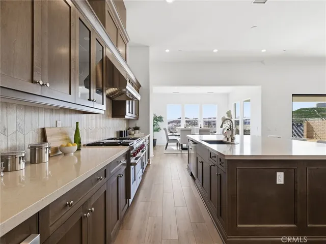 a kitchen with stainless steel appliances granite countertop lots of counter space a sink and dishwasher a stove top oven with wooden floor