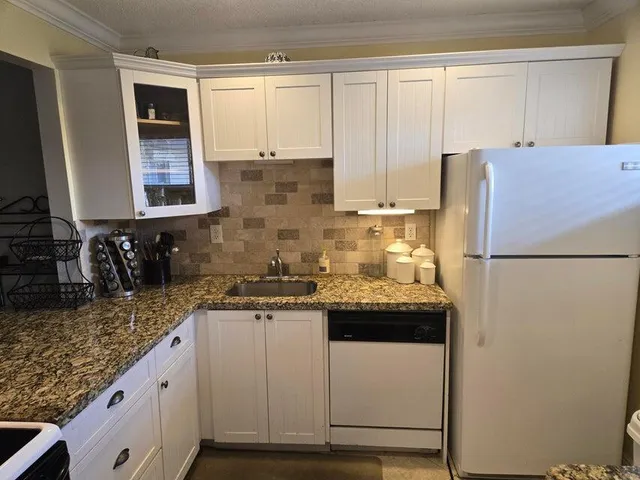 a kitchen with stainless steel appliances granite countertop a sink and a refrigerator