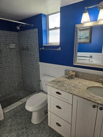 a bathroom with a granite countertop toilet sink and mirror