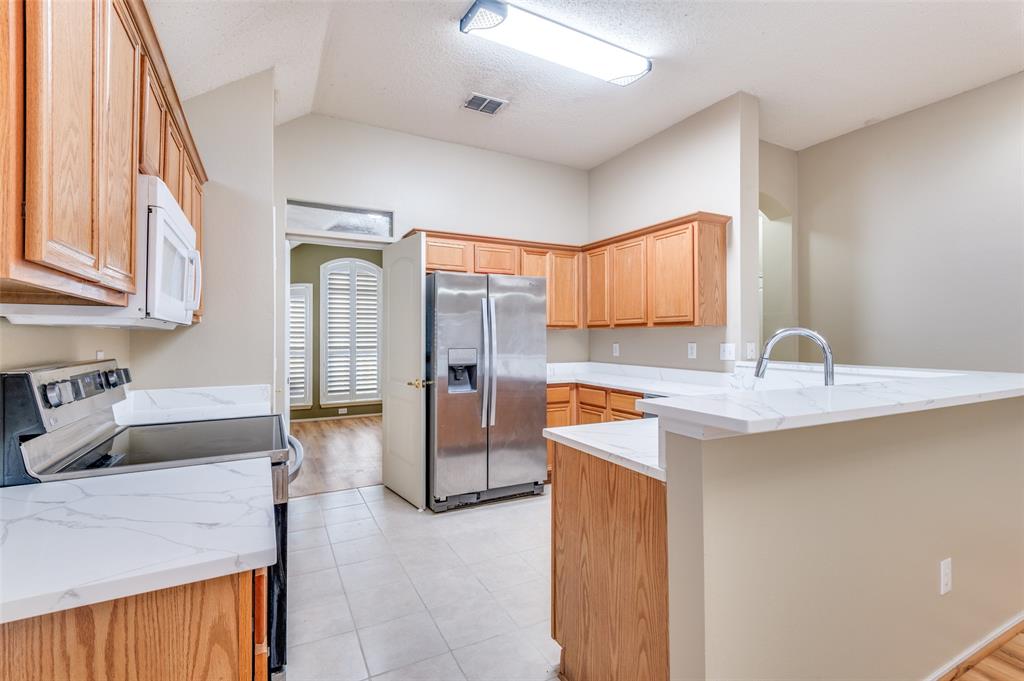 4921 Tulip Lane Fort Worth, TX 76137 - Photo 5 of 12 a kitchen with stainless steel appliances granite countertop a sink and a refrigerator