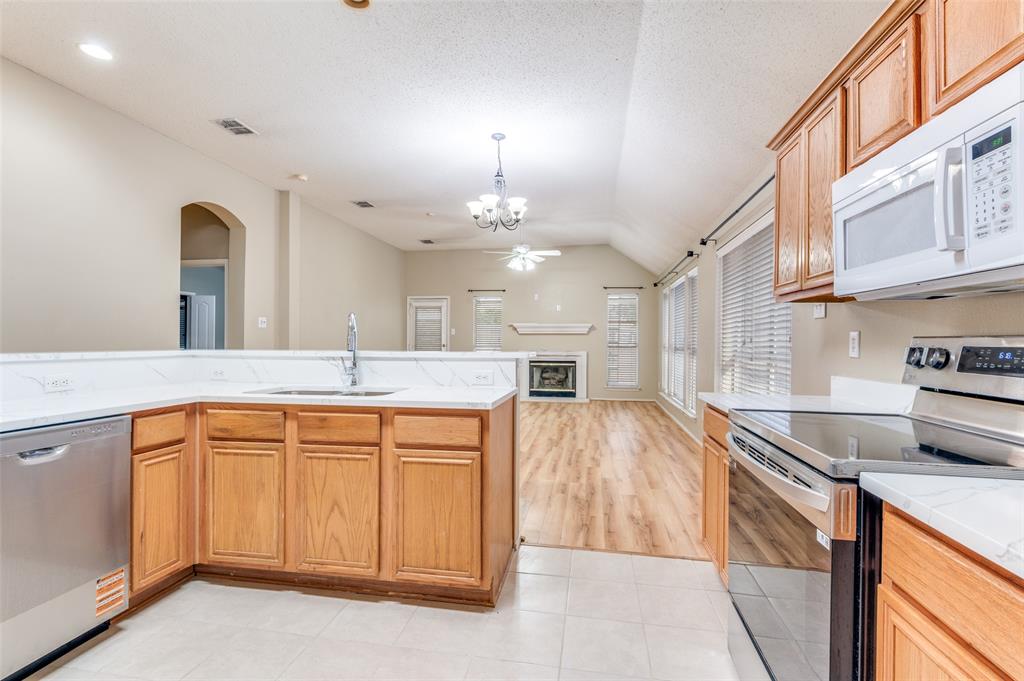 4921 Tulip Lane Fort Worth, TX 76137 - Photo 10 of 12 a large kitchen with stainless steel appliances a large counter top a stove and a sink