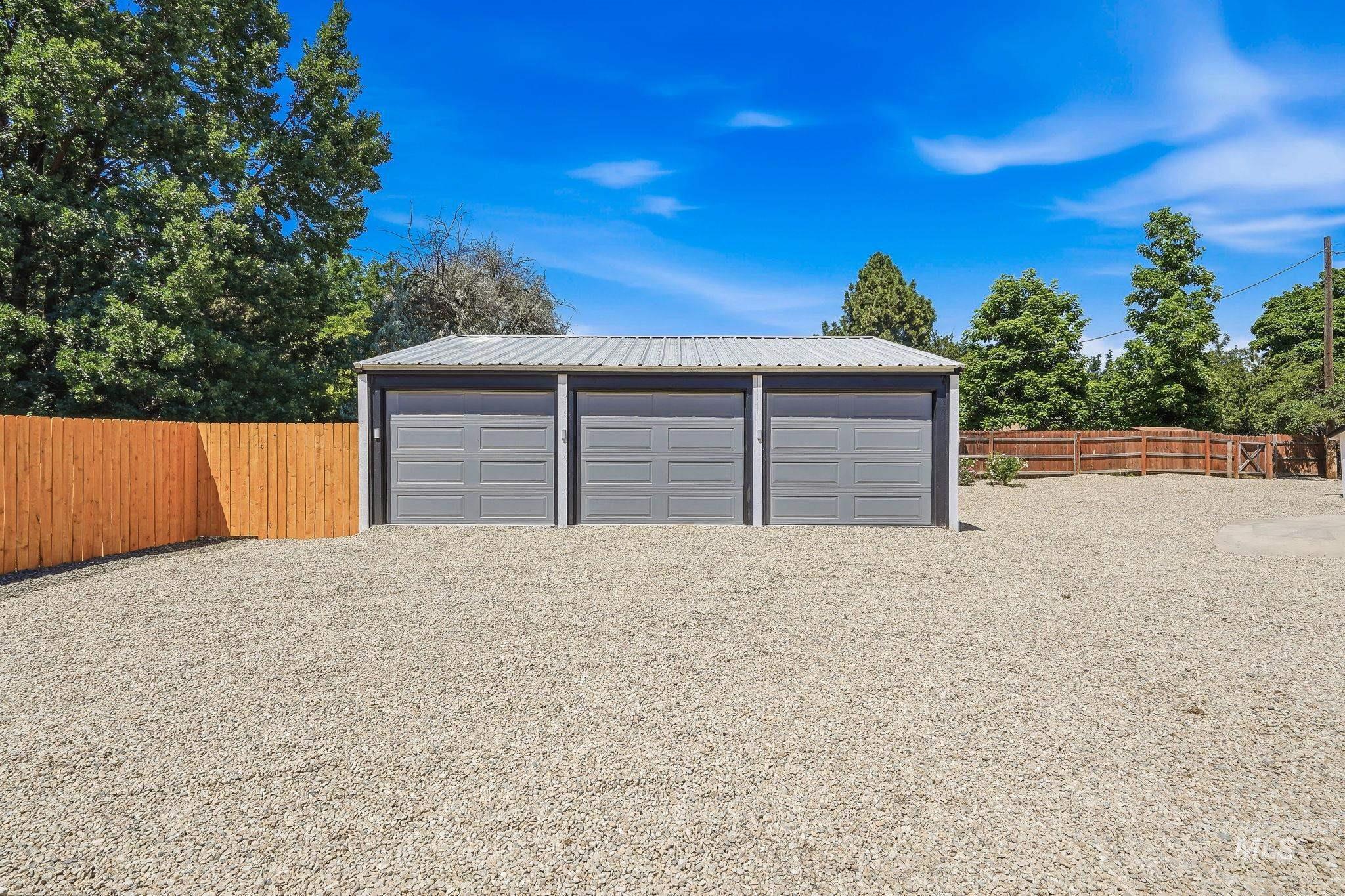 2152 Artesian Road Eagle, ID 83616 - Photo 31 of 50 Three-car garage structure featuring gray overhead doors and a metal roof