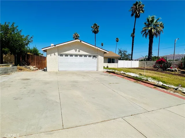 a view of a house with a yard and palm trees