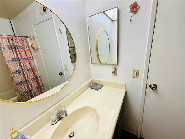 a bathroom with a sink and mirror with bathtub