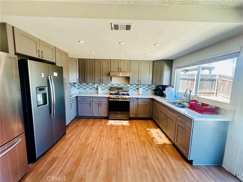 2111 Whitestone Drive Riverside, CA 92506 - Photo 7 of 29 a kitchen with stainless steel appliances granite countertop a refrigerator a sink dishwasher a stove and white countertops with wooden floor