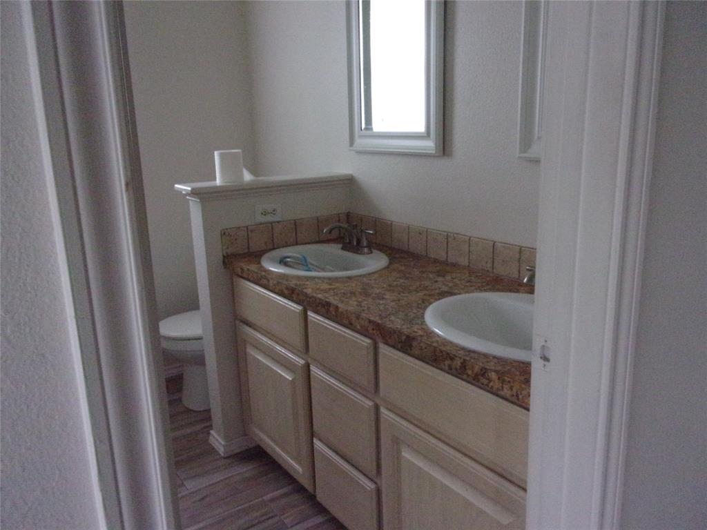 1511 Spanish Oak Drive Granbury, TX 76048 - Photo 10 of 16 a bathroom with a granite countertop sink and a toilet
