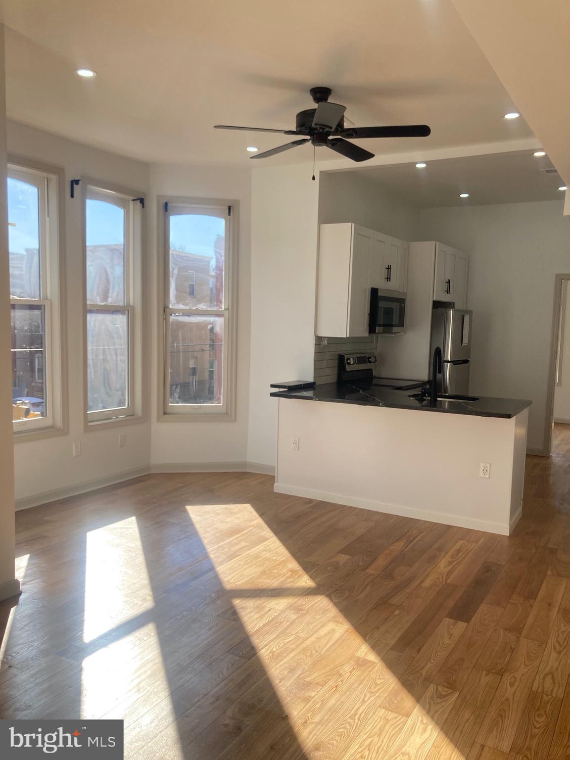 1901 West Diamond Street, Unit 2 Philadelphia, PA 19121 - Photo 2 of 9 a view of a kitchen with kitchen island a sink wooden floor and a large window