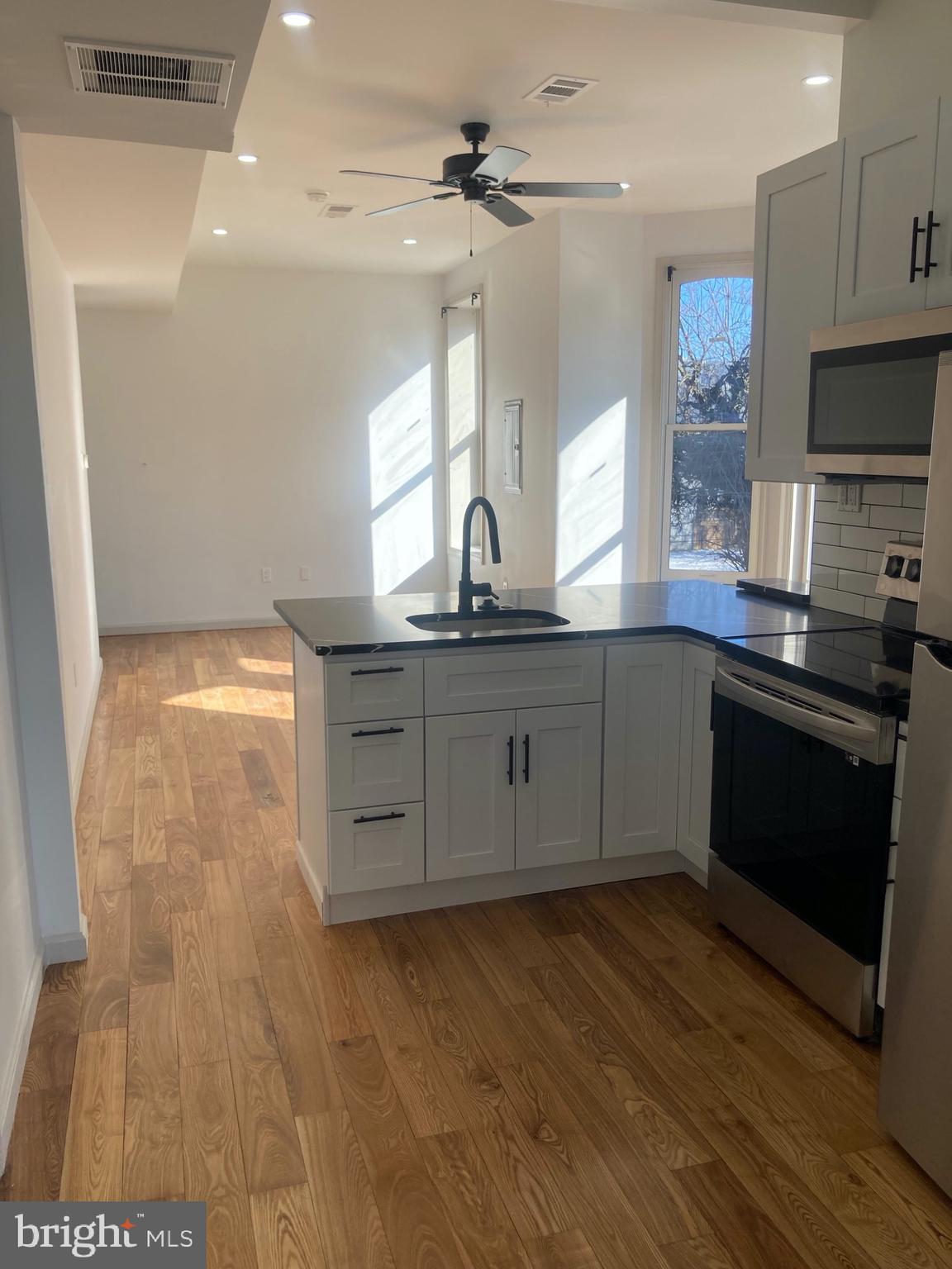 1901 West Diamond Street, Unit 2 Philadelphia, PA 19121 - Photo 3 of 9 a kitchen with stainless steel appliances granite countertop a sink cabinets and wooden floor