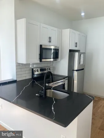 a kitchen with a sink a microwave a refrigerator and white cabinets