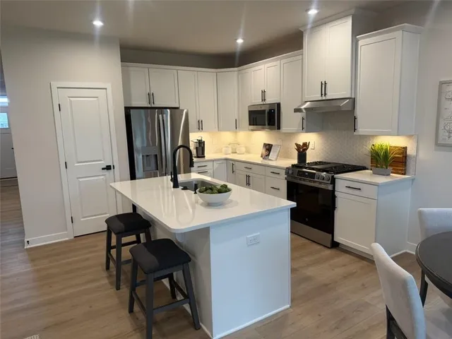a kitchen with a sink a stove a refrigerator and white cabinets with wooden floor