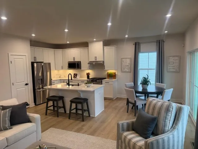 a living room with stainless steel appliances furniture and a view of kitchen