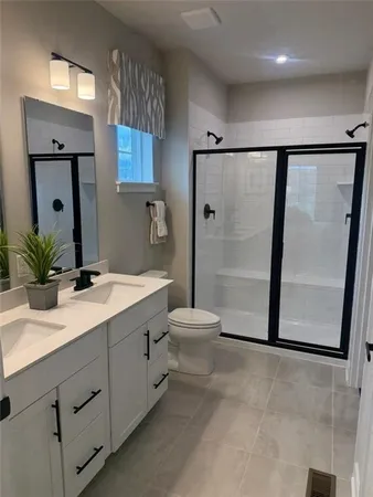 a bathroom with a double vanity sink toilet and shower