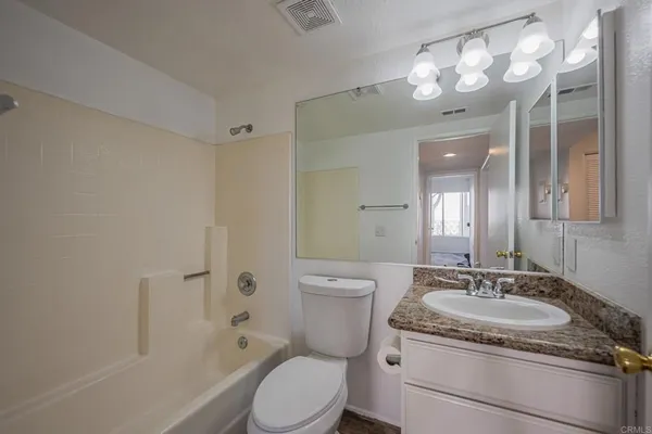 a bathroom with a granite countertop sink toilet a mirror a vanity and shower