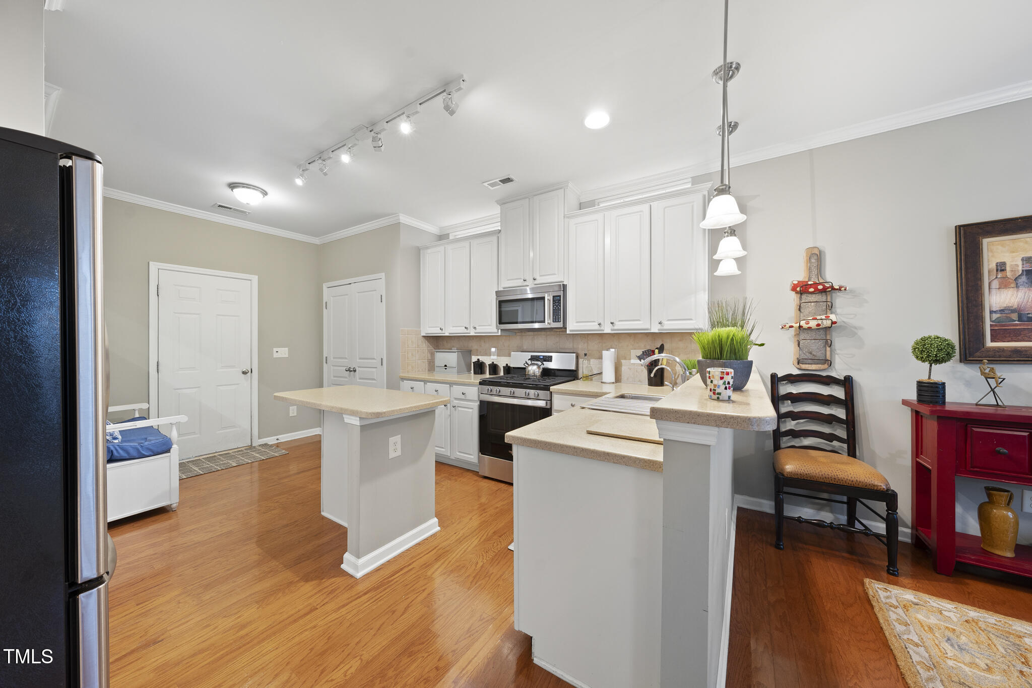 3419 Ranbir Drive Durham, NC 27713 - Photo 8 of 33 a kitchen with a refrigerator a stove and a dining table with wooden floor