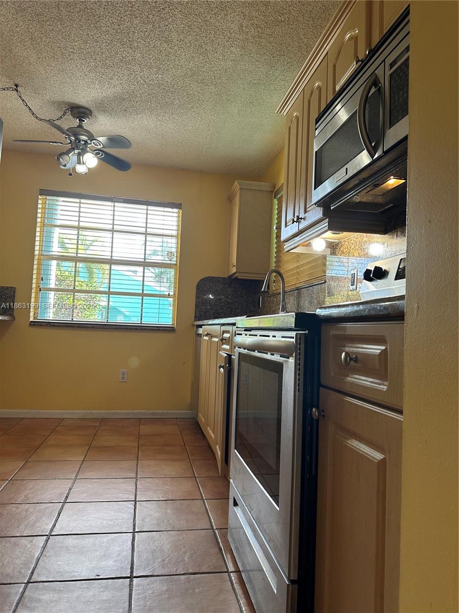 2653 Southeast 20th Court, Unit 105D Homestead, FL 33035 - Photo 13 of 16 a kitchen with a stove top oven cabinets and a window