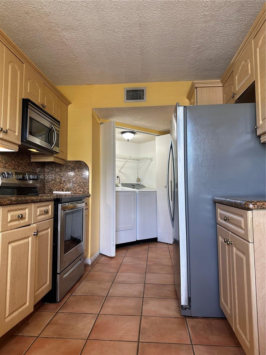 2653 Southeast 20th Court, Unit 105D Homestead, FL 33035 - Photo 14 of 16 a kitchen with granite countertop a refrigerator and a stove top oven
