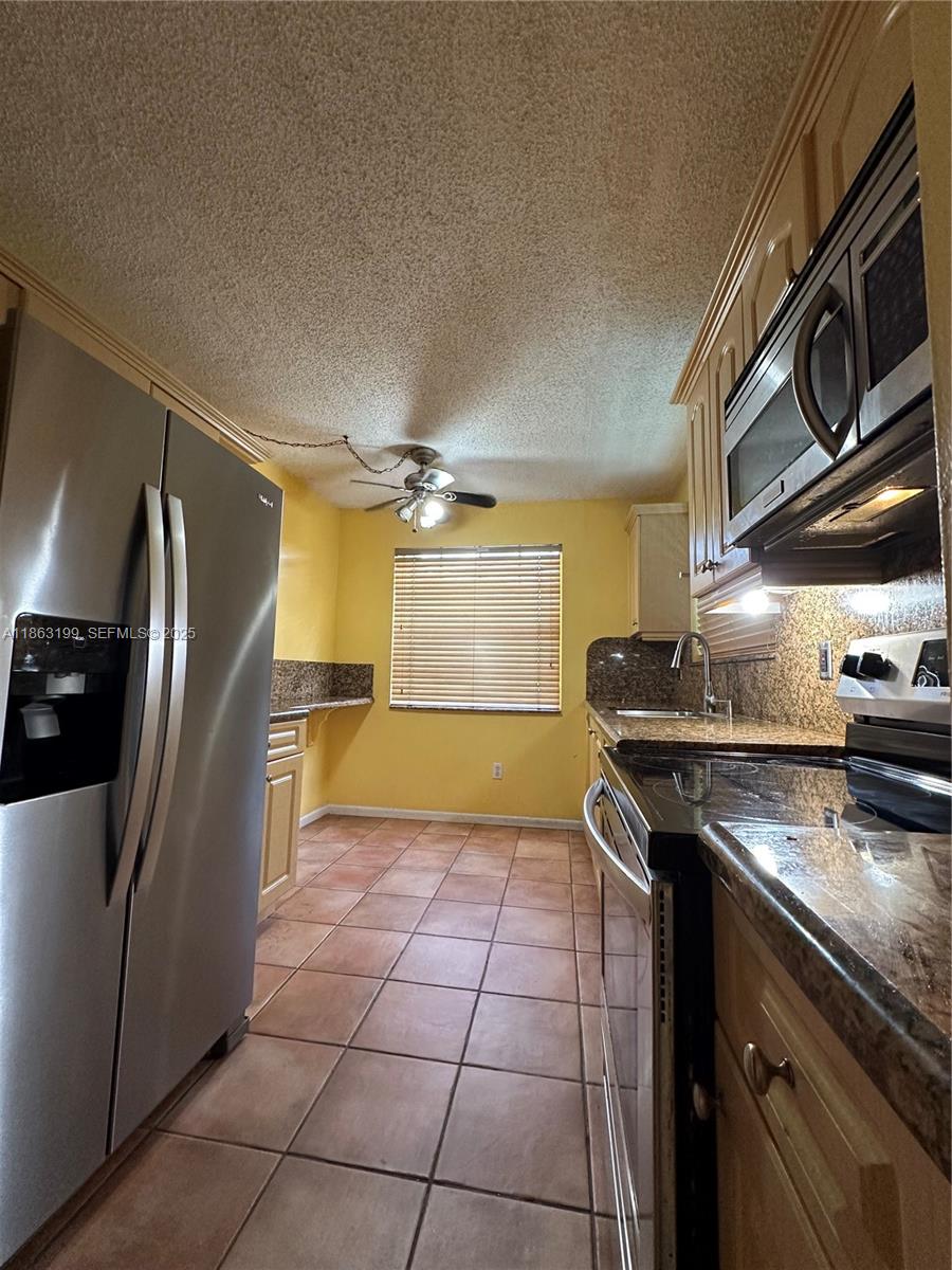 2653 Southeast 20th Court, Unit 105D Homestead, FL 33035 - Photo 3 of 16 a kitchen with a stove a sink and a refrigerator