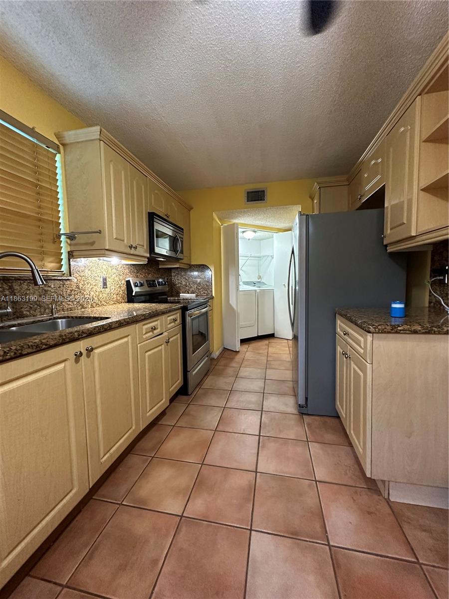 2653 Southeast 20th Court, Unit 105D Homestead, FL 33035 - Photo 5 of 16 a kitchen with stainless steel appliances granite countertop a sink and cabinets