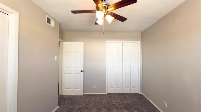 an empty room with closet and a chandelier fan
