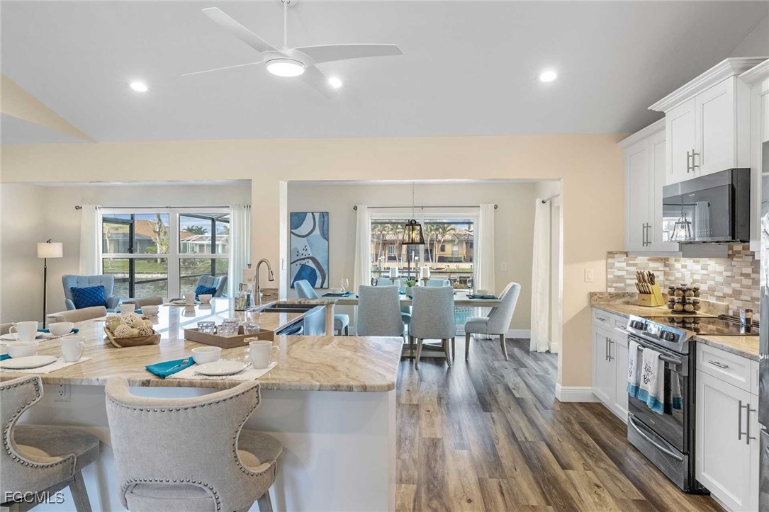 2307 Southwest 40th Street Cape Coral, FL 33914 - Photo 33 of 36 a kitchen with a table chairs stove and white cabinets