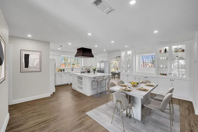 a open dining room with stainless steel appliances kitchen island granite countertop a table chairs and a refrigerator
