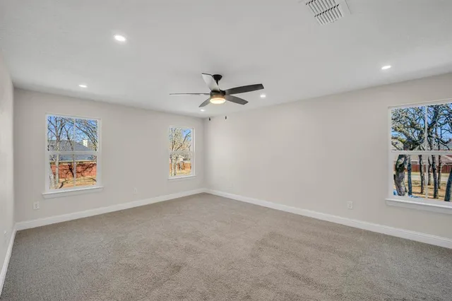 an empty room with windows and fan