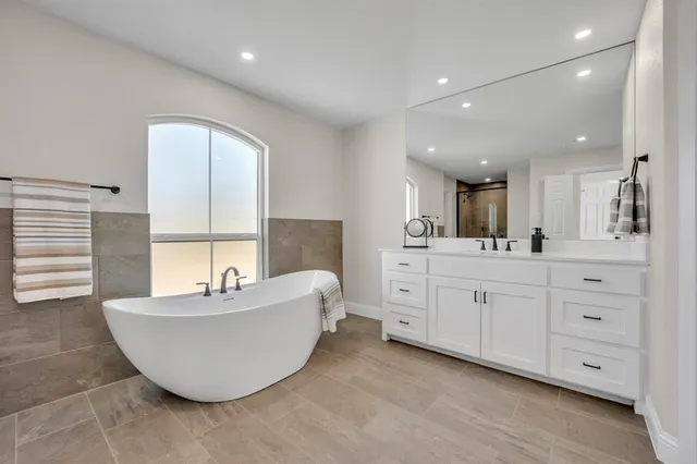 a spacious bathroom with a double vanity sink a mirror and a bathtub
