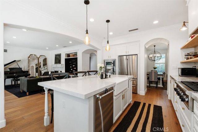 a large kitchen with kitchen island a stove a sink a refrigerator and a wooden floor