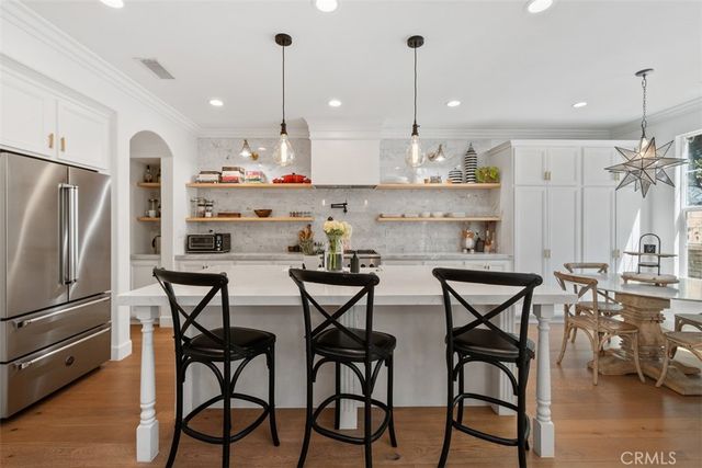 a kitchen with stainless steel appliances kitchen island a table chairs sink and cabinets