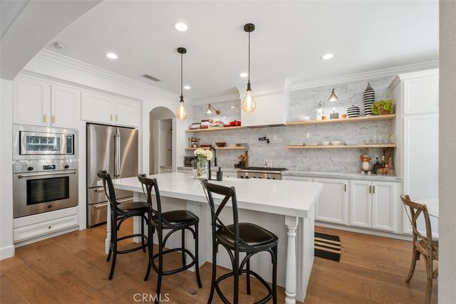 a kitchen with stainless steel appliances kitchen island granite countertop a table chairs stove and refrigerator