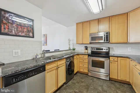 a kitchen with stainless steel appliances granite countertop a sink a stove and a refrigerator