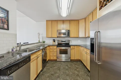 a kitchen with stainless steel appliances granite countertop a stove a sink and a refrigerator