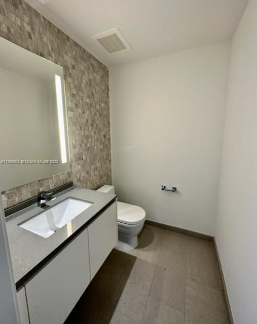 68 Southeast 6th Street, Unit 2507 Miami, FL 33131 - Photo 26 of 46 a bathroom with a granite countertop sink toilet and mirror
