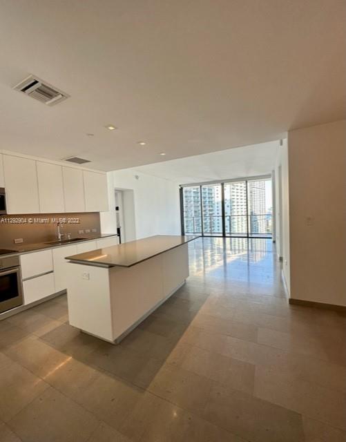 68 Southeast 6th Street, Unit 2507 Miami, FL 33131 - Photo 4 of 46 a large white kitchen with granite countertop a large white cabinets and white appliances