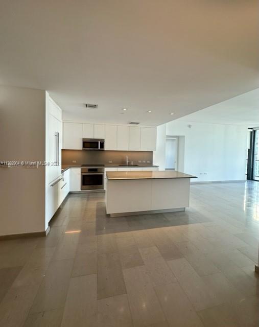 68 Southeast 6th Street, Unit 2507 Miami, FL 33131 - Photo 9 of 46 a large kitchen with stainless steel appliances granite countertop a refrigerator sink and white cabinets