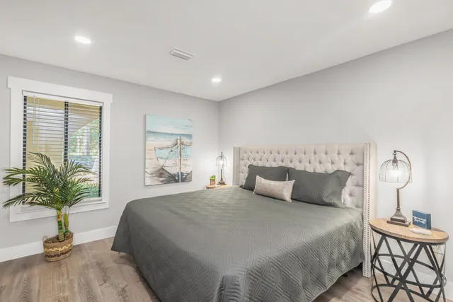 a large bedroom with wooden floor and windows