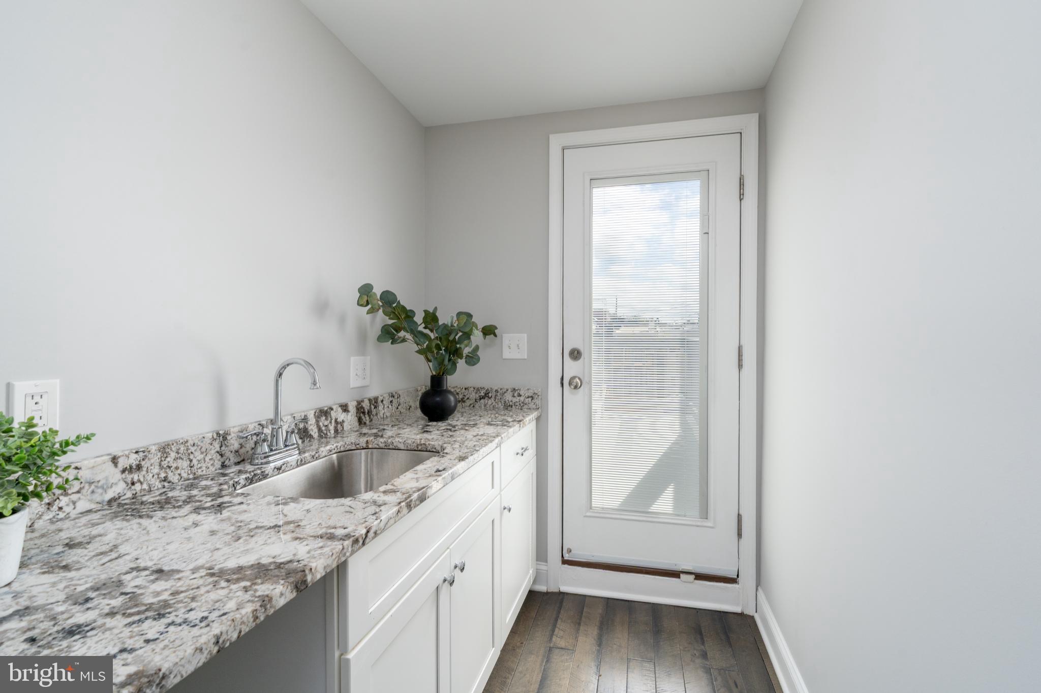 23 South Washington Street Baltimore, MD 21231 - Photo 29 of 57 a bathroom with a granite countertop sink a mirror and shower